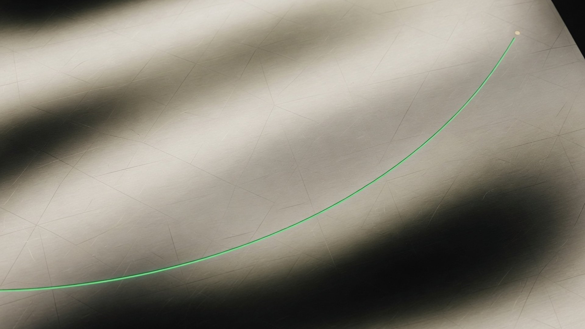 Brushed aluminium surface with a green performance curve rising from lower left to upper right